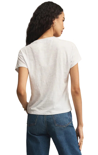 Woman wearing a white t-shirt and blue jeans against a beige background