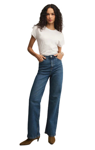 Woman wearing a white t-shirt and blue jeans on a beige background