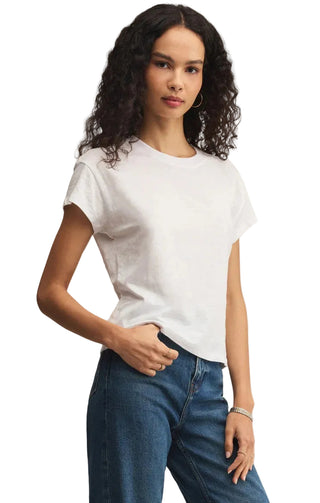 Woman wearing a white t-shirt and blue jeans against a beige background
