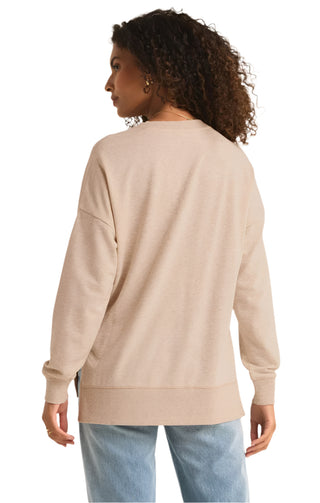 Woman wearing a beige sweater and light blue jeans on a beige background