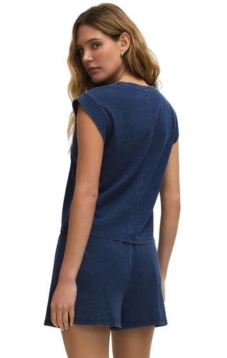 Woman wearing a blue sleeveless top and shorts set on a beige background