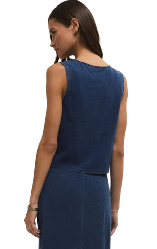 Woman wearing a blue sleeveless dress against a plain background