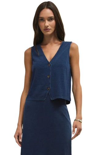 Woman wearing a blue sleeveless top and skirt set against a plain background