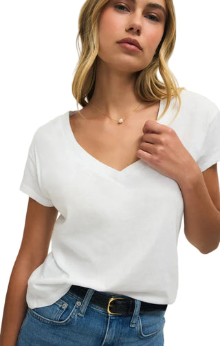 Woman wearing a white t-shirt and blue jeans against a plain background