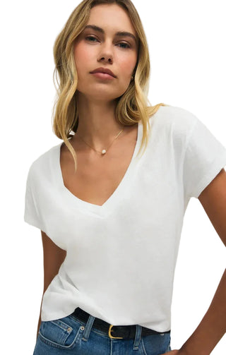 Woman wearing a white top and blue jeans against a plain background