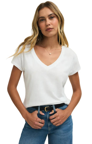 Woman wearing a white t-shirt and blue jeans against a plain background