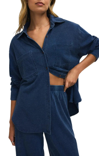 Woman wearing a blue corduroy shirt and pants on a plain background