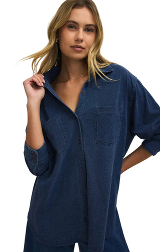 Woman wearing a blue denim shirt against a beige background