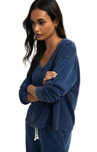 Woman wearing a blue sweatshirt and pants against a plain background