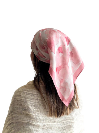 Person wearing a pink and white patterned headscarf on a plain background