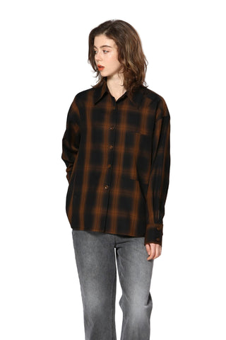 Person wearing a brown and black plaid shirt with gray pants on a white background