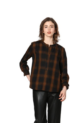 Woman wearing a brown plaid shirt and black pants on a white background