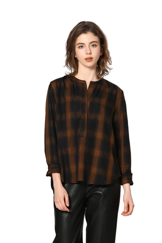 Woman wearing a brown and black checkered blouse with black pants on a white background