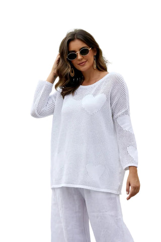 Woman in a white outfit standing outdoors with palm trees in the background