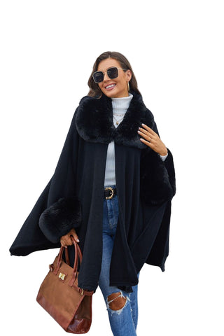 Woman wearing a black coat with fur collar against a white wall