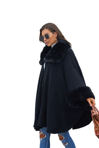 Woman wearing a black coat with fur trim against a light gray wall