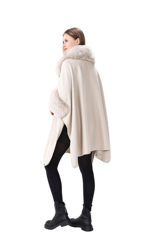 Woman wearing a beige cape with fur trim on a white background