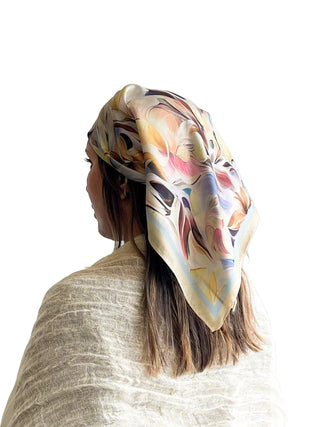 Woman wearing a colorful floral scarf on her head against a white background