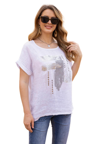 Woman wearing a white t-shirt with a graphic design and blue jeans in front of a beige wall.