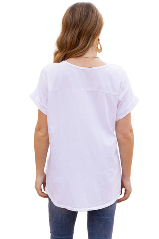 Woman wearing a white t-shirt and blue jeans standing in front of a beige wall.