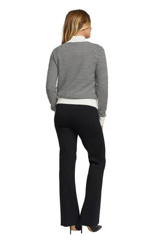 Person wearing a black and white striped sweater and black pants on a light gray background
