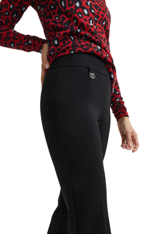 Person wearing a red leopard print top and black pants on a white background
