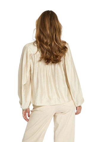 Woman wearing a beige blouse and pants against a white background