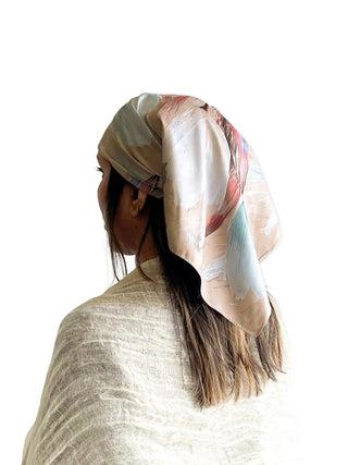 Person wearing a patterned headscarf on a plain background