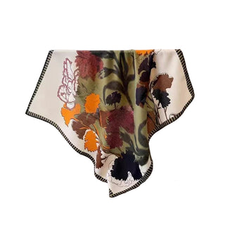 Floral-patterned blanket draped over a surface with a handbag and photo frame in the background.