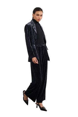 Woman wearing a black velvet suit with a white background
