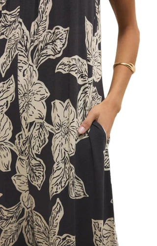 Close-up of a black dress with beige floral pattern, worn by a person.